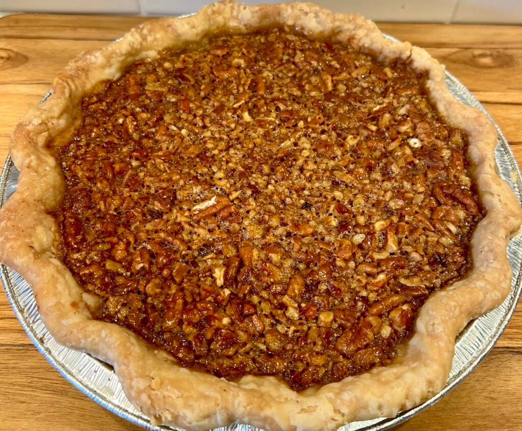 Homemade classic pecan pie with a golden, flaky crust and toasted pecan filling in a glass pie dish.